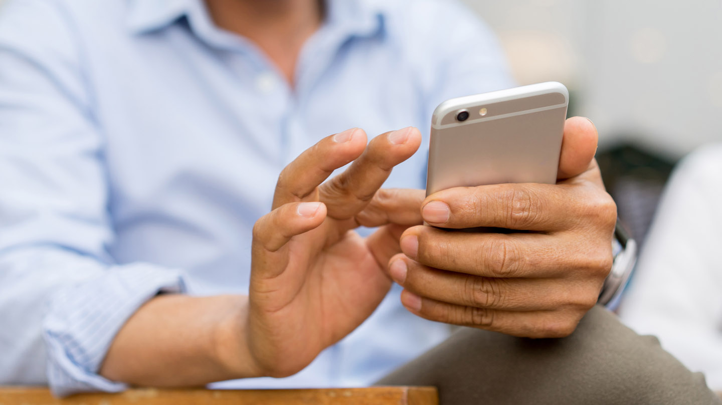 Mann in blauem Hemd tippt mit Fingern auf einem Smartphone. Mann in blauem Hemd tippt mit Fingern auf einem Smartphone.